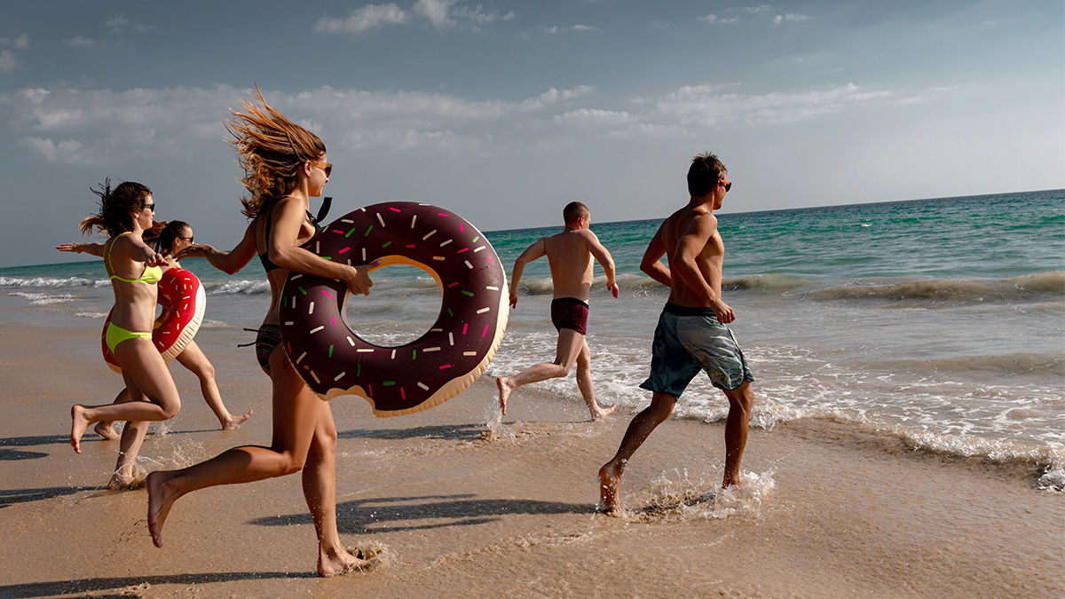 Skupina priateľov nadšene beží z pláže do mora. Sú na letnej low budget dovolenke.