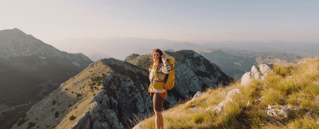 Turistka s batohom na horách, pred sebou má krásny výhľad.