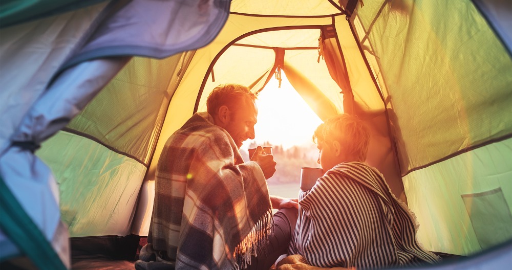 Otec so synom sedia v stane zakrytý dekou a pijú nápoj.