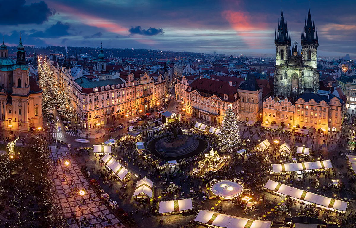 Nočný dronový záber zachytávajúci množstvo rozsvietených vianočných stánkov na Staromestskom námestí v Prahe. 