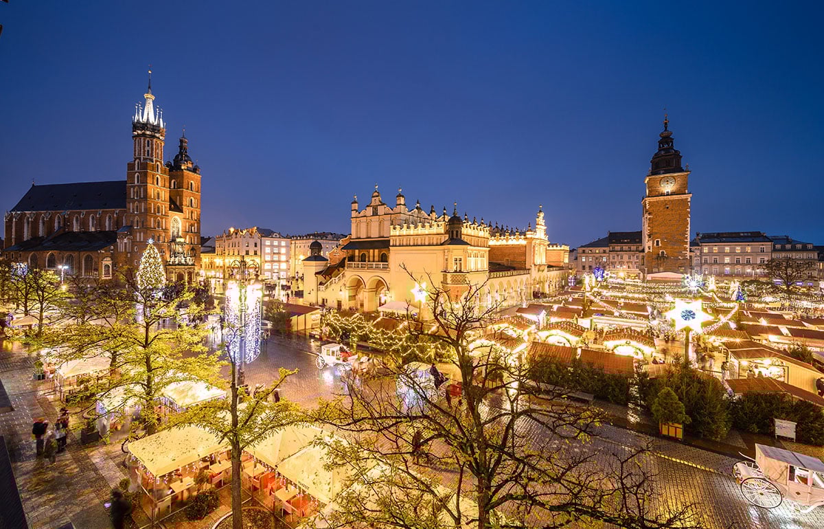 Nočná ulica Krakowa s rozsvietenými vianočnými stánkami.