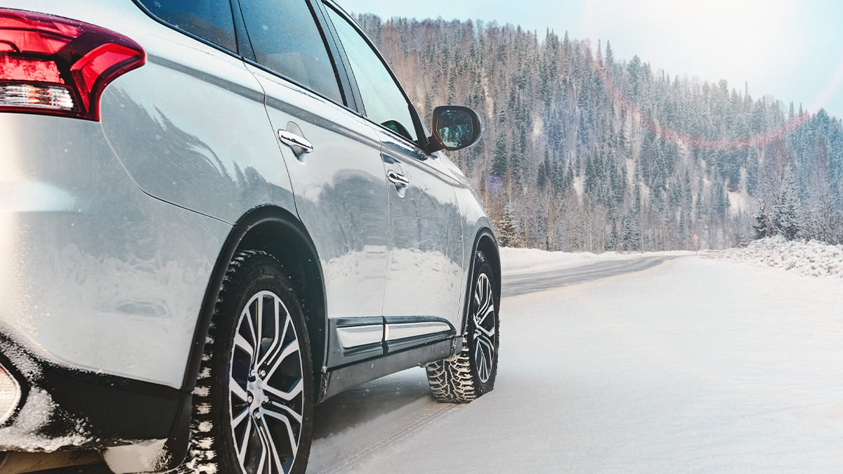 Detail na pneumatiky bieleho auta idúce po zasneženej vozovke.