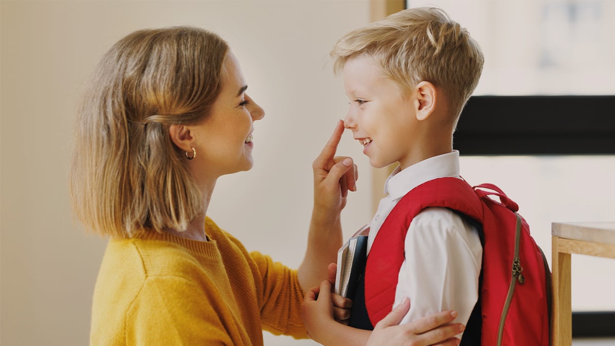 Mama vyprevádza synčeka do školy, jemne sa mu dotýka nosa, atmosféra je veselá a usmievavá.