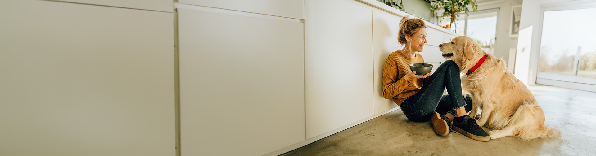 zena s usmevom v byte sedi na zemi so psom