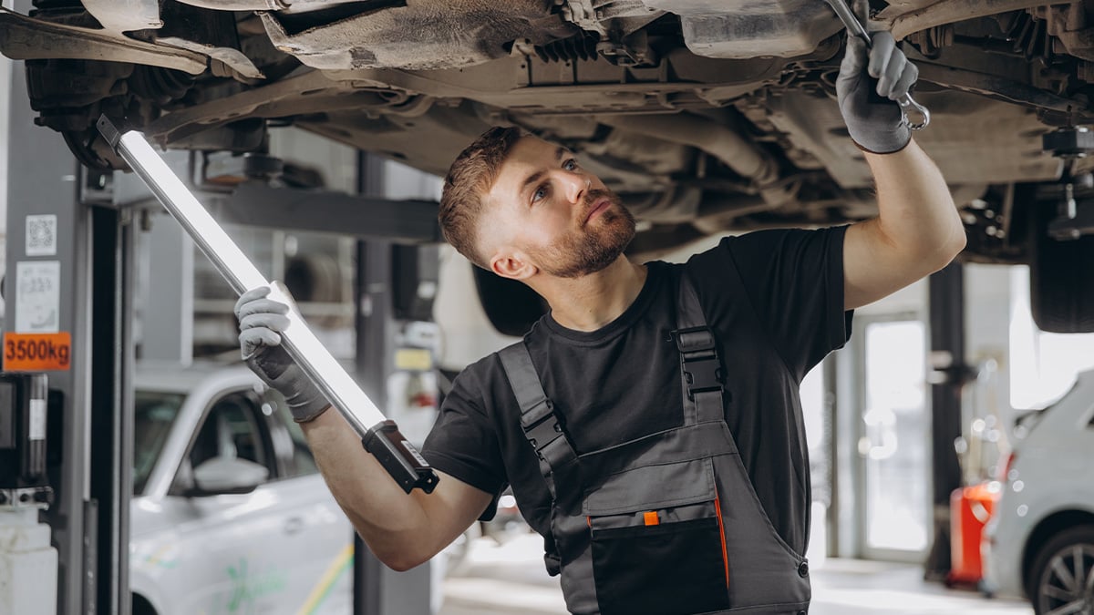 Mechanik kontroluje podvozok auta v rámci technickej a emisnej kontroly.