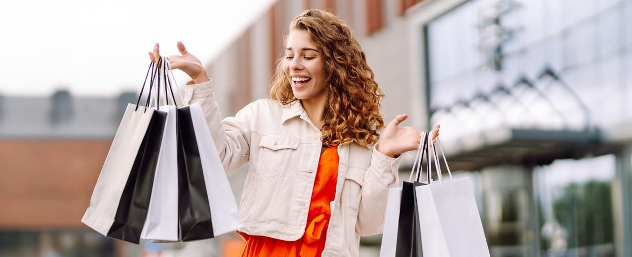 Usmievajúca sa žena s množstvom nákupných tašiek v rukách. Vracia sa z nákupov v obchodnom centre.