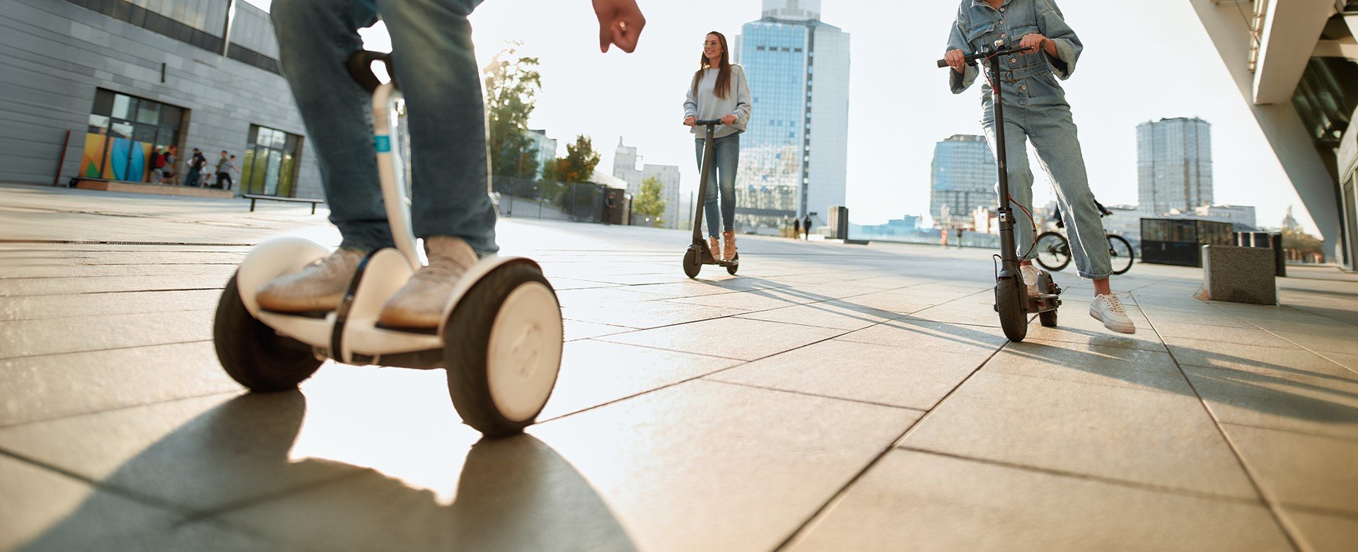 azdci na elektrických kolobežkách a jazdec na segwayi nachádzajúci sa v meste pri východe slnka.