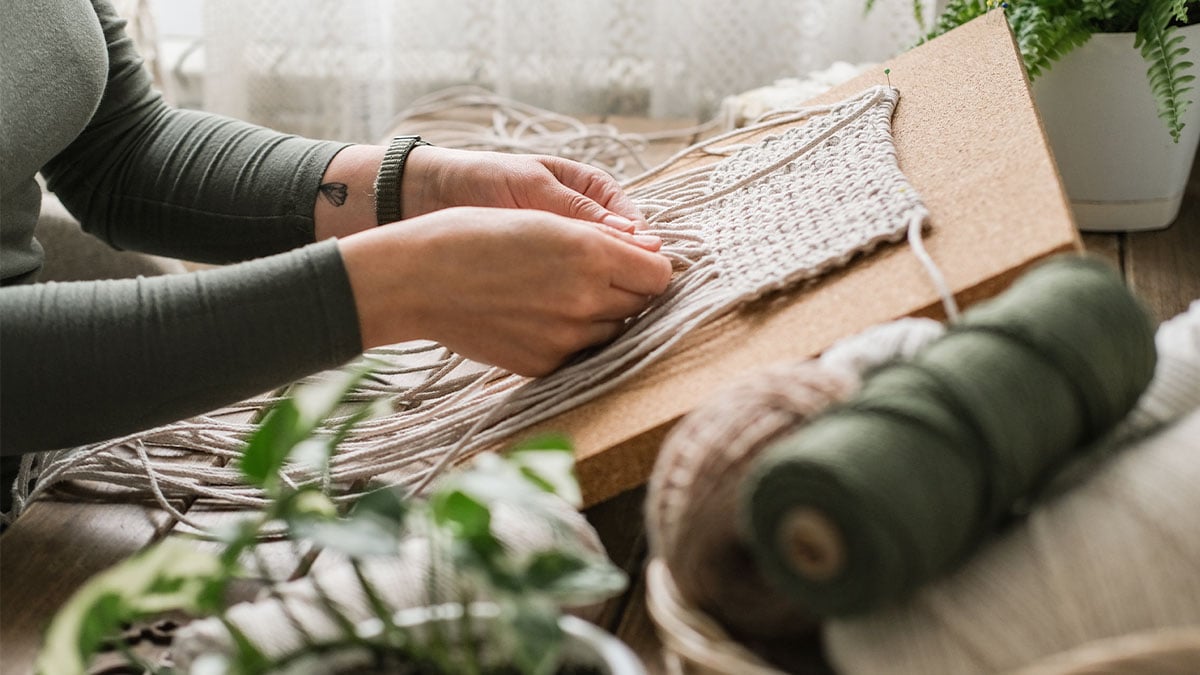Ženské ruky splietajú vlnu na štýl makramé.