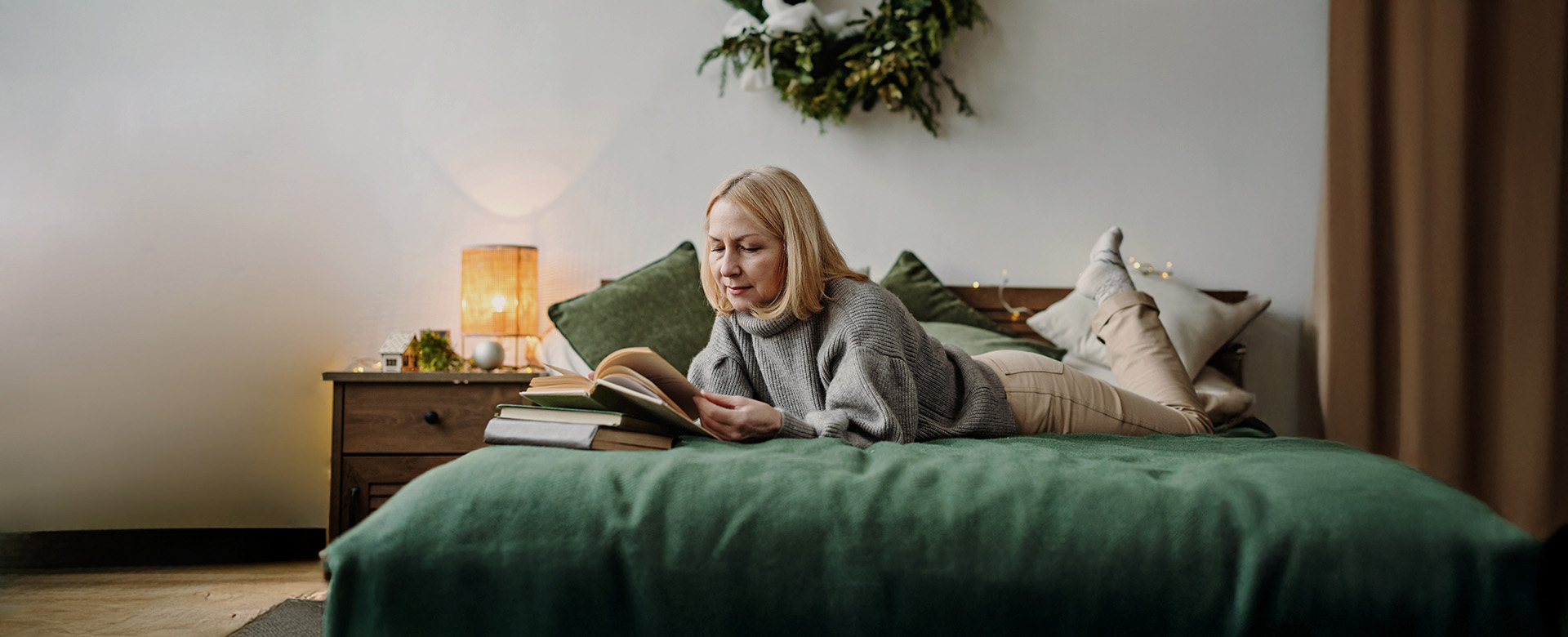 Žena čítajúca počas Vianoc knihu v pohodlí postele.