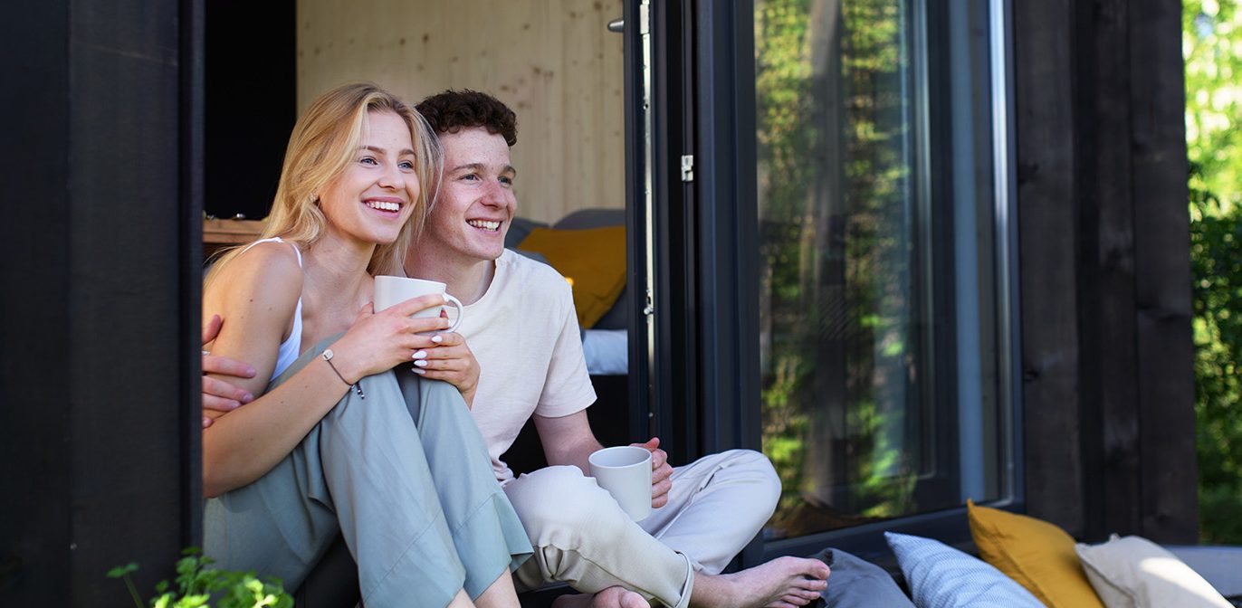 Mladý pár sa usmieva a pozerá smerom von.