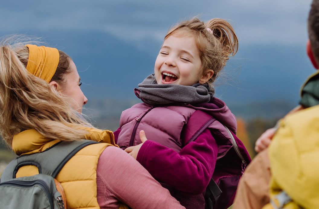 Dievčatko sa smeje na rukách ženy.