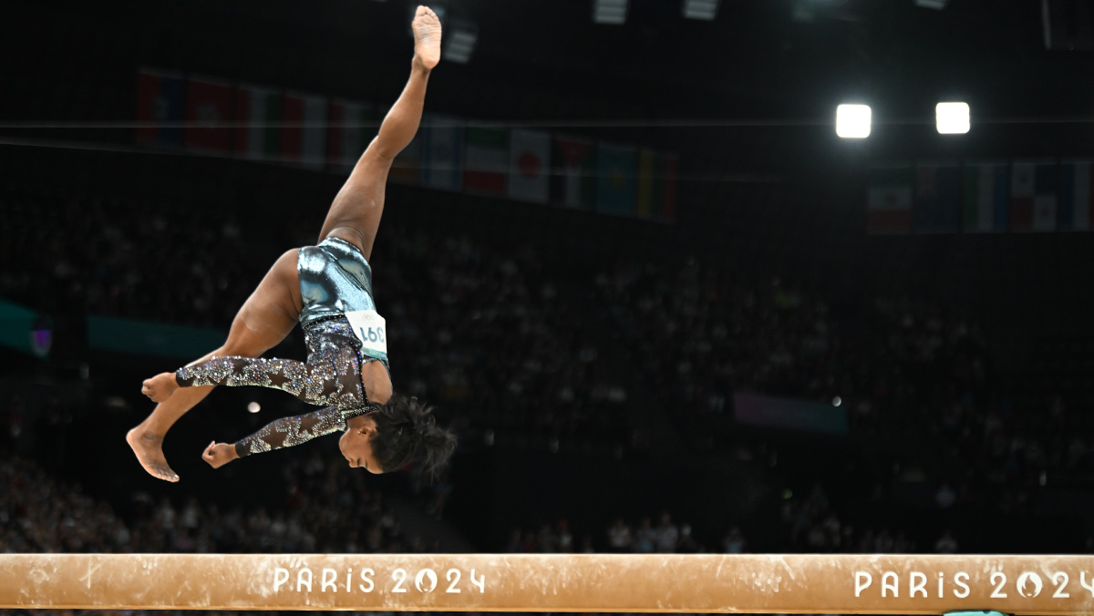 Simone Biles zachytená uprostred náročného gymnastického prvku.