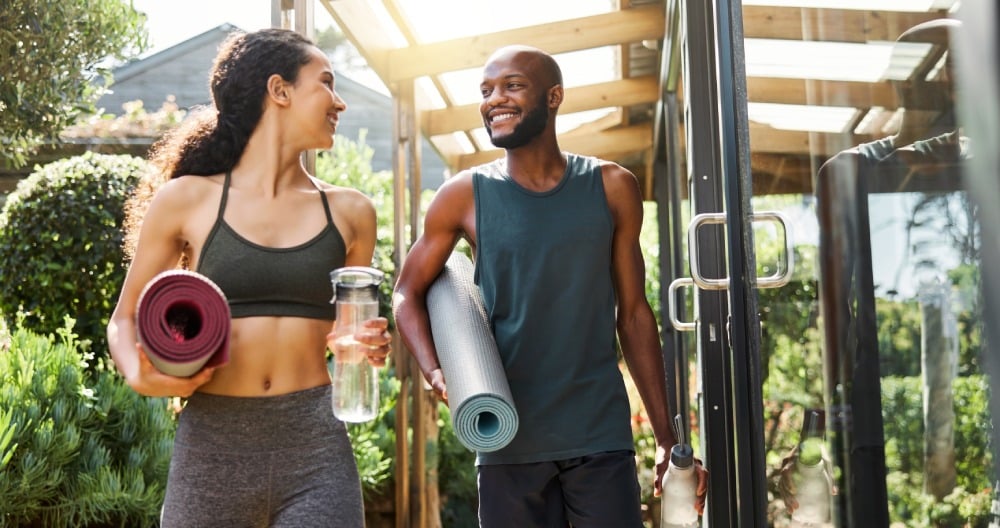 Žena s mužom držia v ruke športové pomôcky a fľaše s vodou.