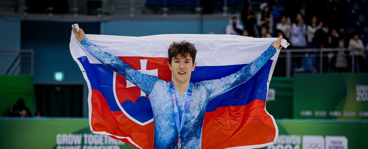 Adam Hagara pózuje so slovenskou vlajkou rozprestretou za chrbtom.