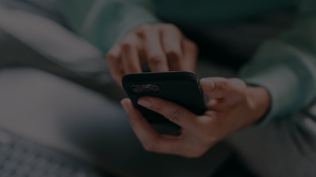Detailný záber na ruky mladého muža, ktorý scrolluje na mobile.