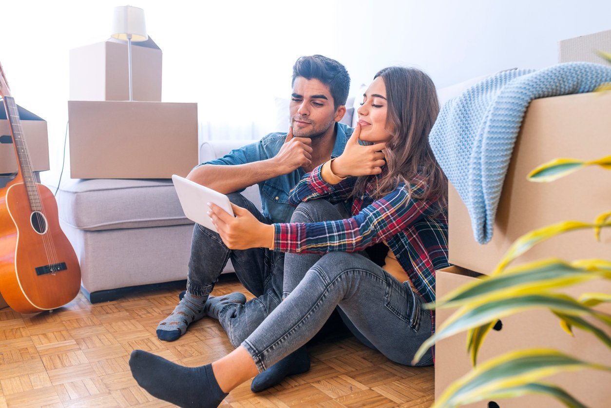 zena a muz sedia na zemi a pozerajú do tabletu