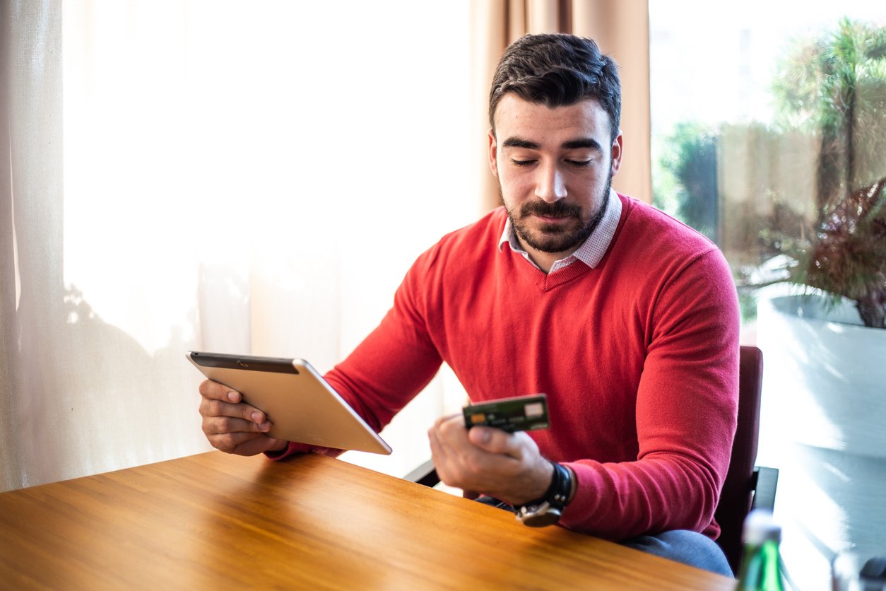 muz sedi za stolom a pozera na platobnu kartu, v ruke drzi notes