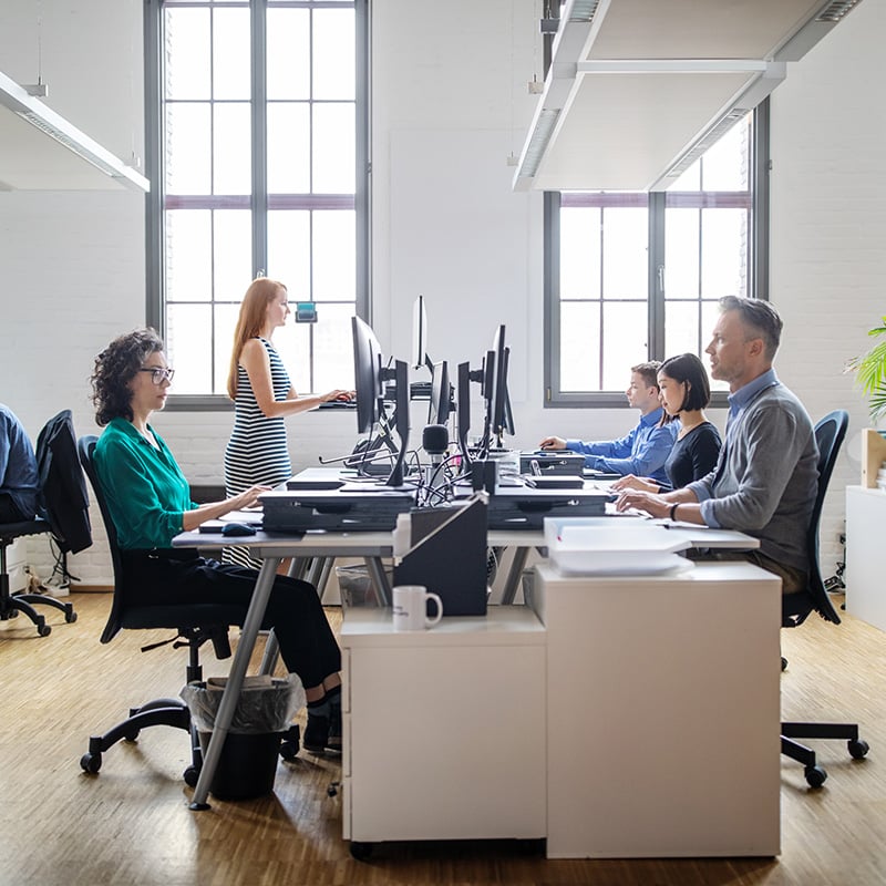 zamestnanci sedia v office za stolmi