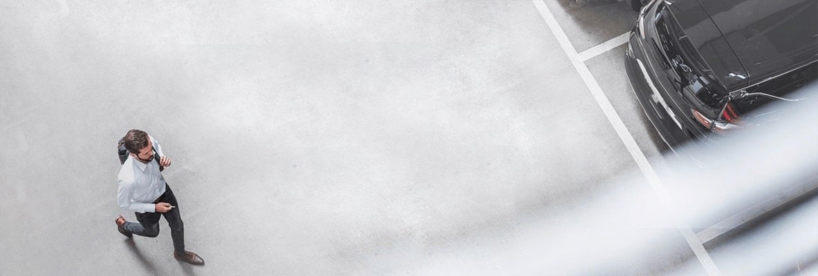 Muz kraca na parkovisku ku autu.