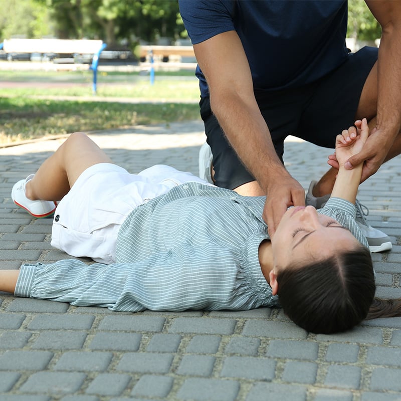 zena leziaca na zemi, muz sa k nej naklana a skusa jej pulz na krku