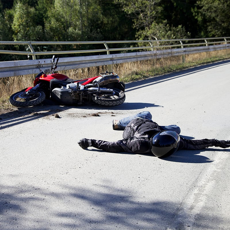 dopravna nehoda motorkára - lezí na ceste a vedľa neho motorka