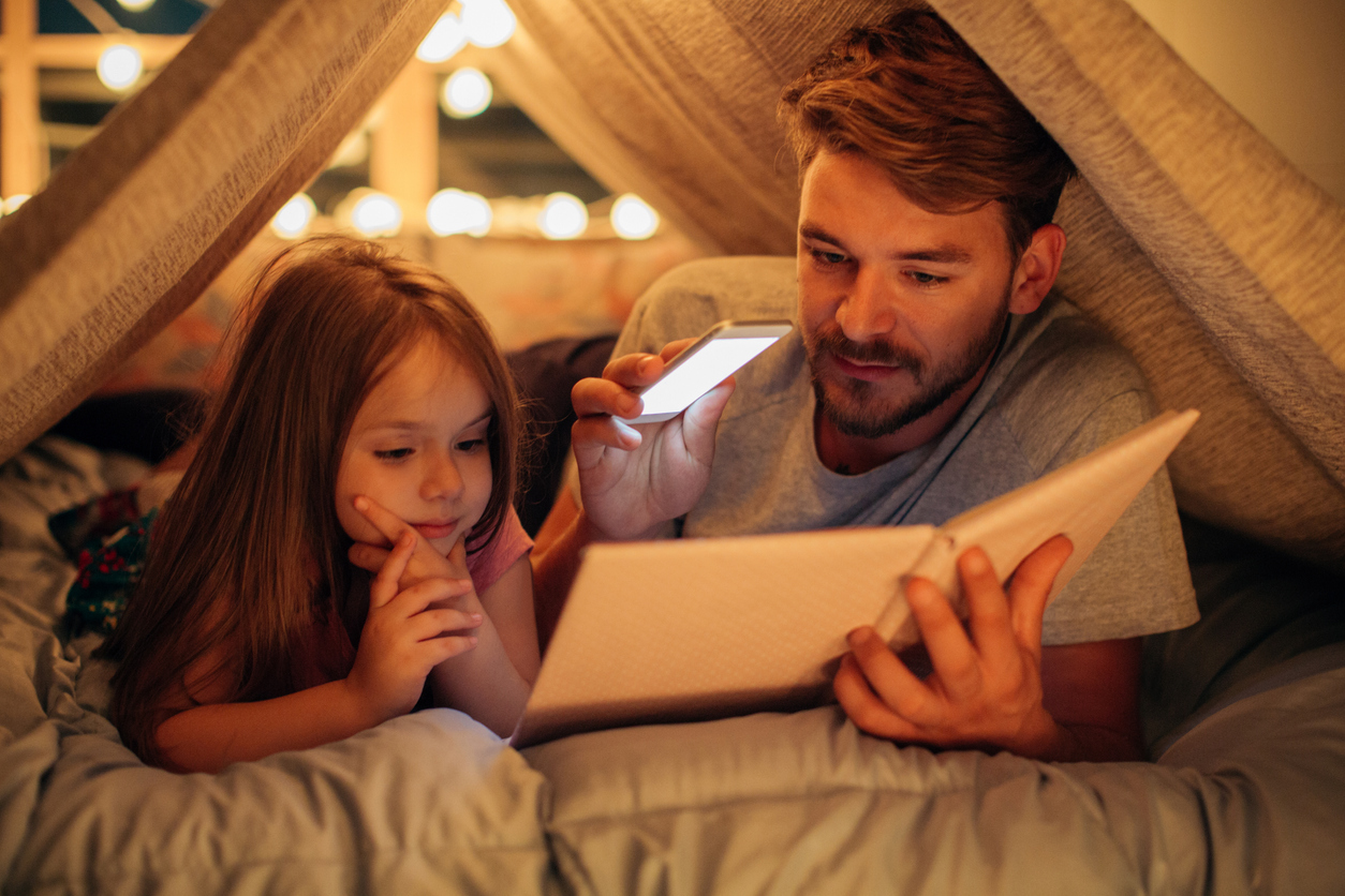 otec a dcera si citaju knihu doma v posteli