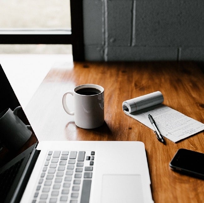 pocitac, kava, zapisnik a pero na stole