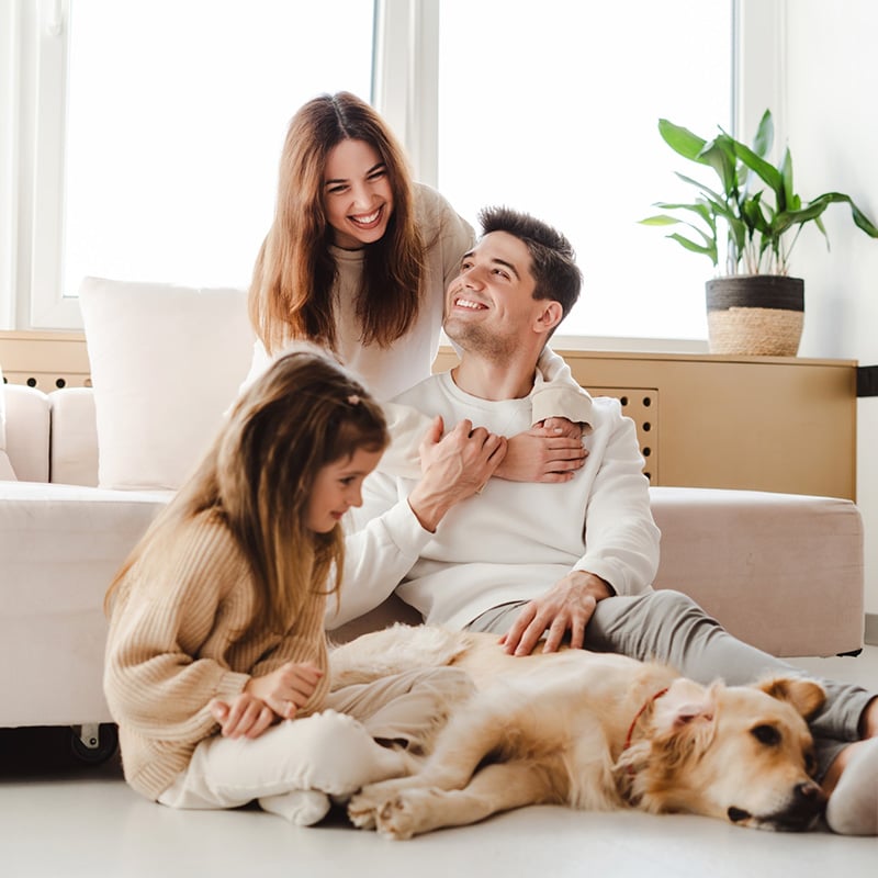 šťastná rodina v obývačke sediaca na zemi so psom