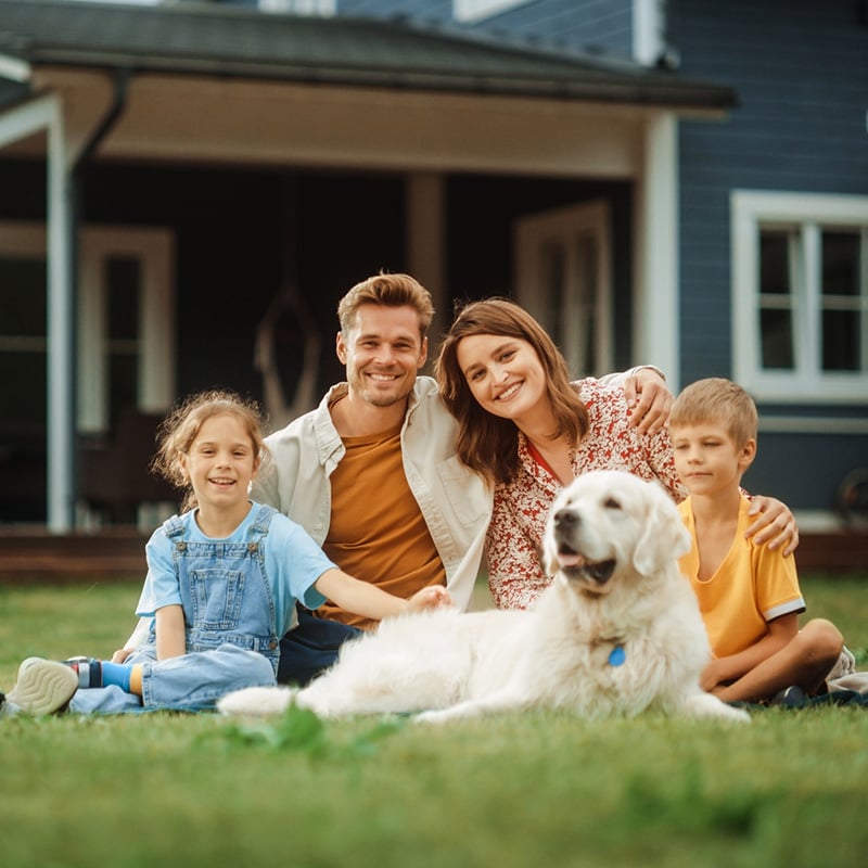 mladá rodina rodičia s dcérou a synom, ležiaci na tráve pred domom so psíkom