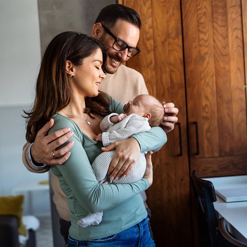 šťastný a umievajúci sa otec s mamou, mama má v naručí novonarodené dieťa