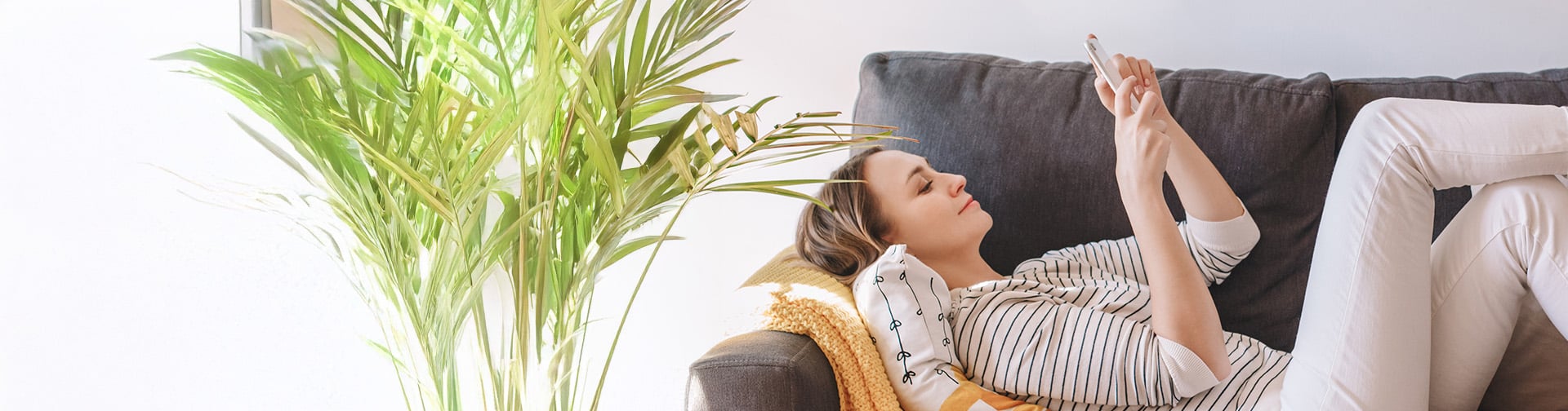 Relaxujuca žena. lezí na pohovke a pozera do mobilu
