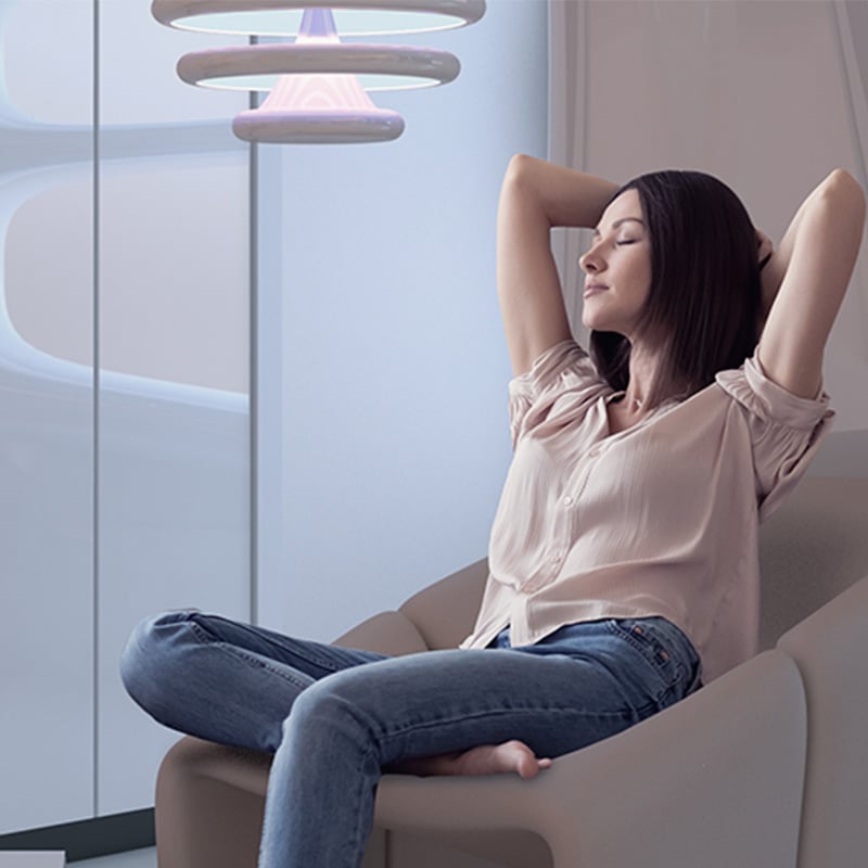 zena relaxuje v kresle, ruky ma za hlavou, oci zatvorene