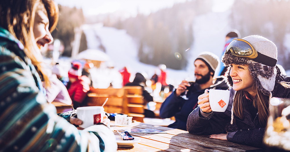 Partia priateľov popíja horúce nápoje v bufete na lyžiarskom svahu.